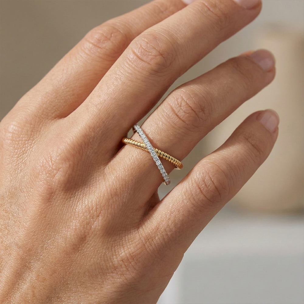 Hand wearing a gold and diamond ring on a neutral background