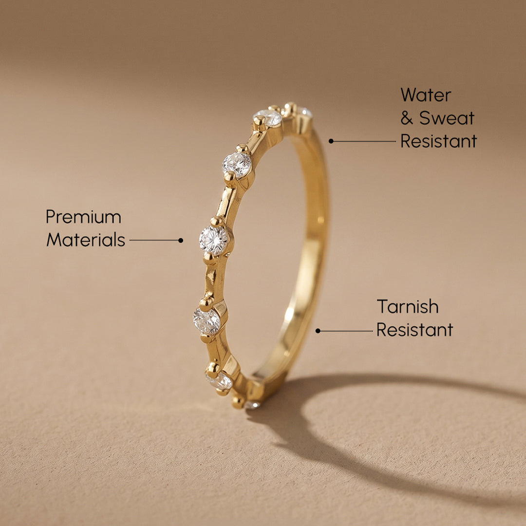 Gold ring with diamonds on a beige background, highlighting features like waterproofness and gold purity.