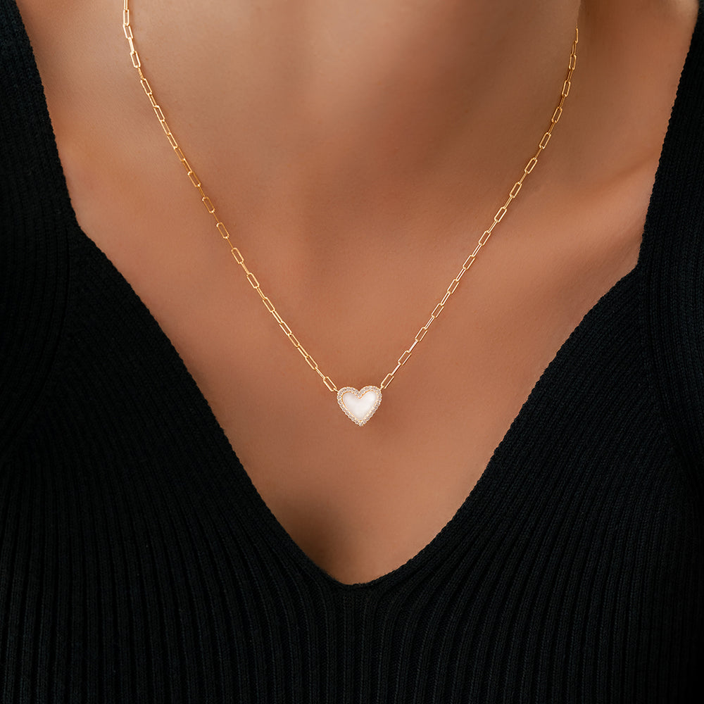 Gold necklace with a heart pendant on a mannequin wearing a black top.