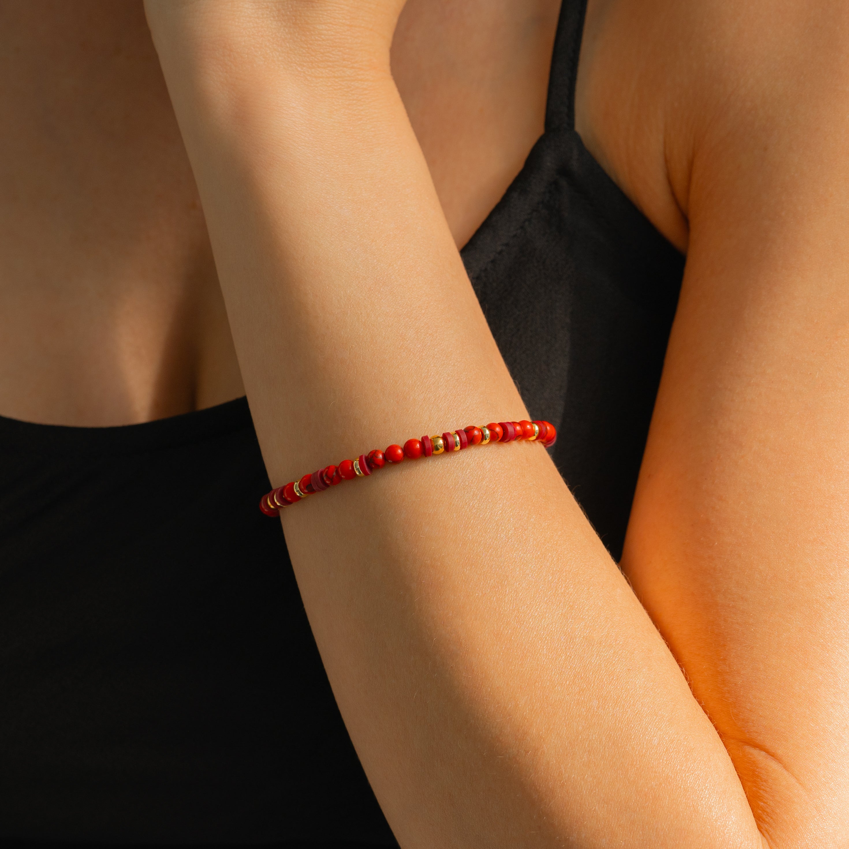 Red beaded bracelet on a wrist with a brown sleeve and light background