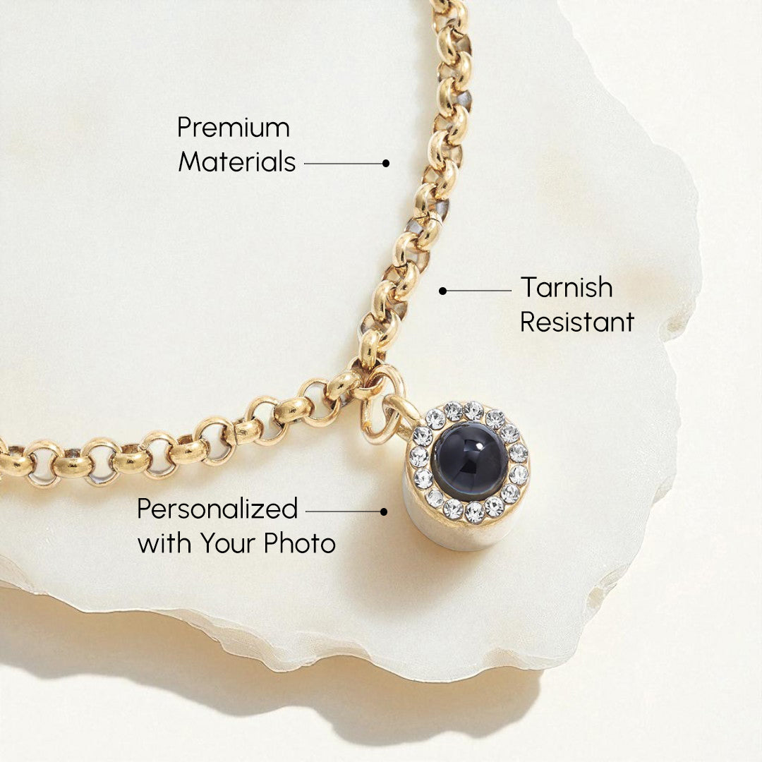 Gold necklace with a black gemstone pendant on a white shell background