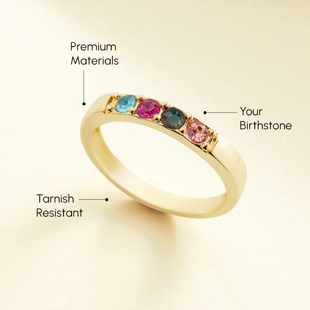 Gold ring with birthstones on a beige background