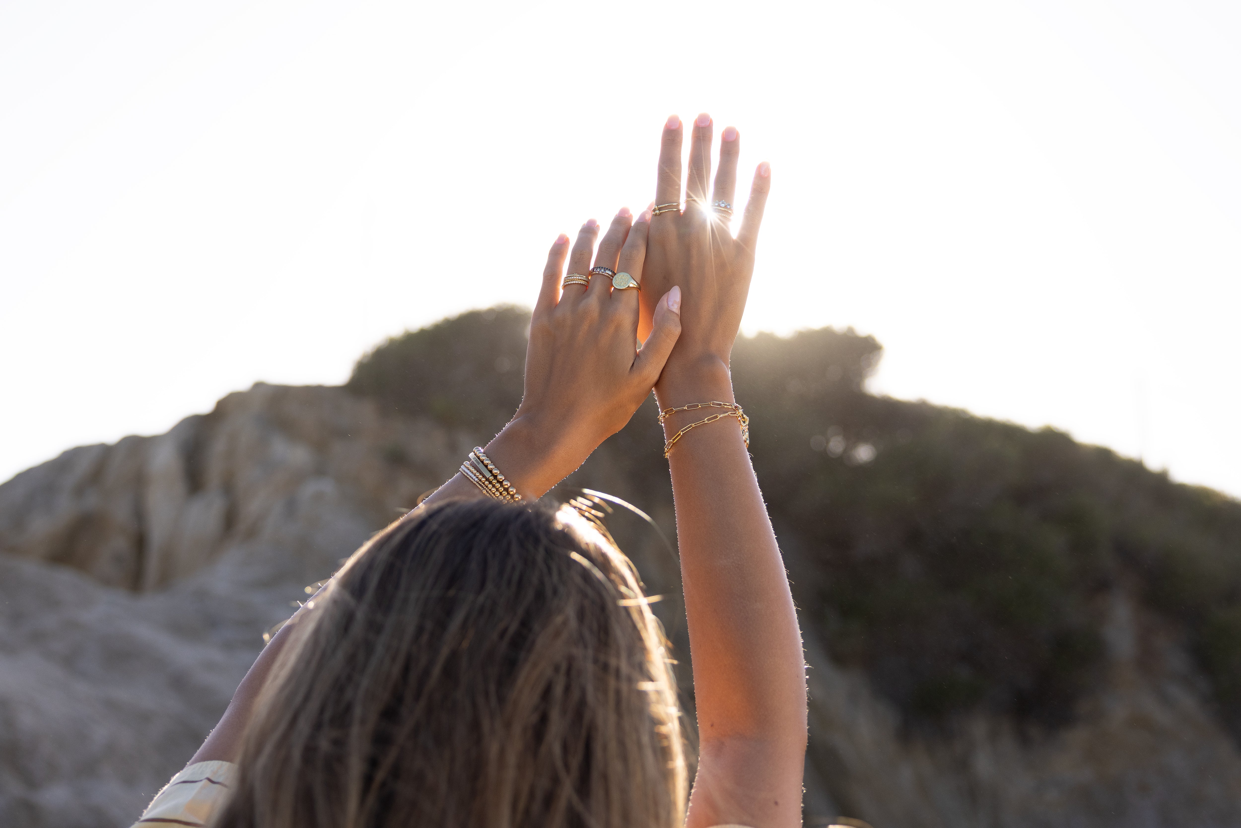 women raising hands in the air to showcase rings and bracelets