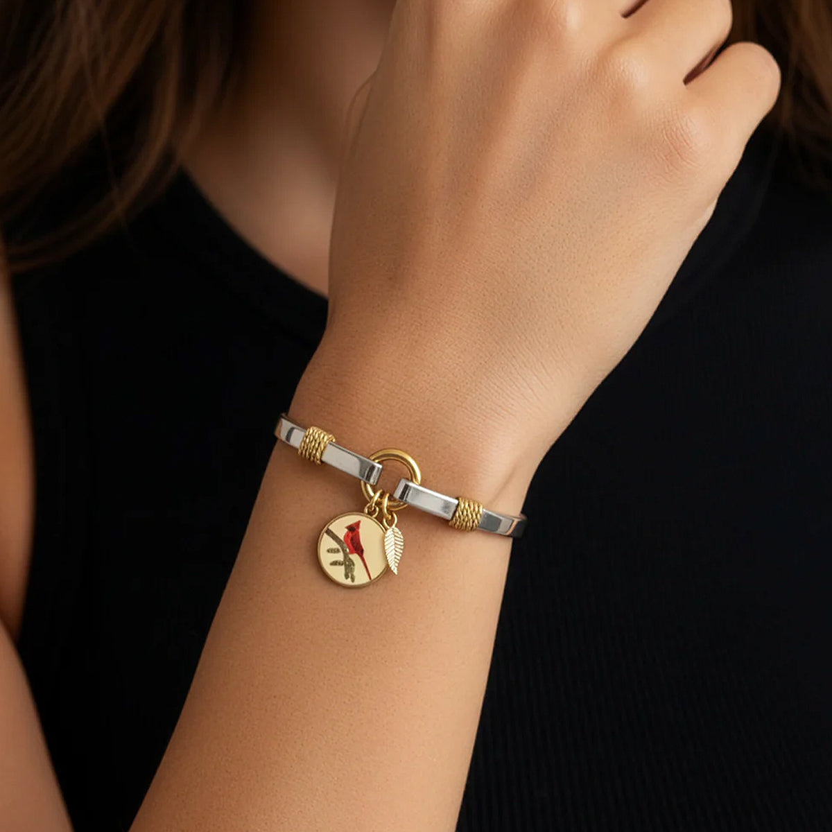 Bracelet with a red apple charm on a wrist against a black background
