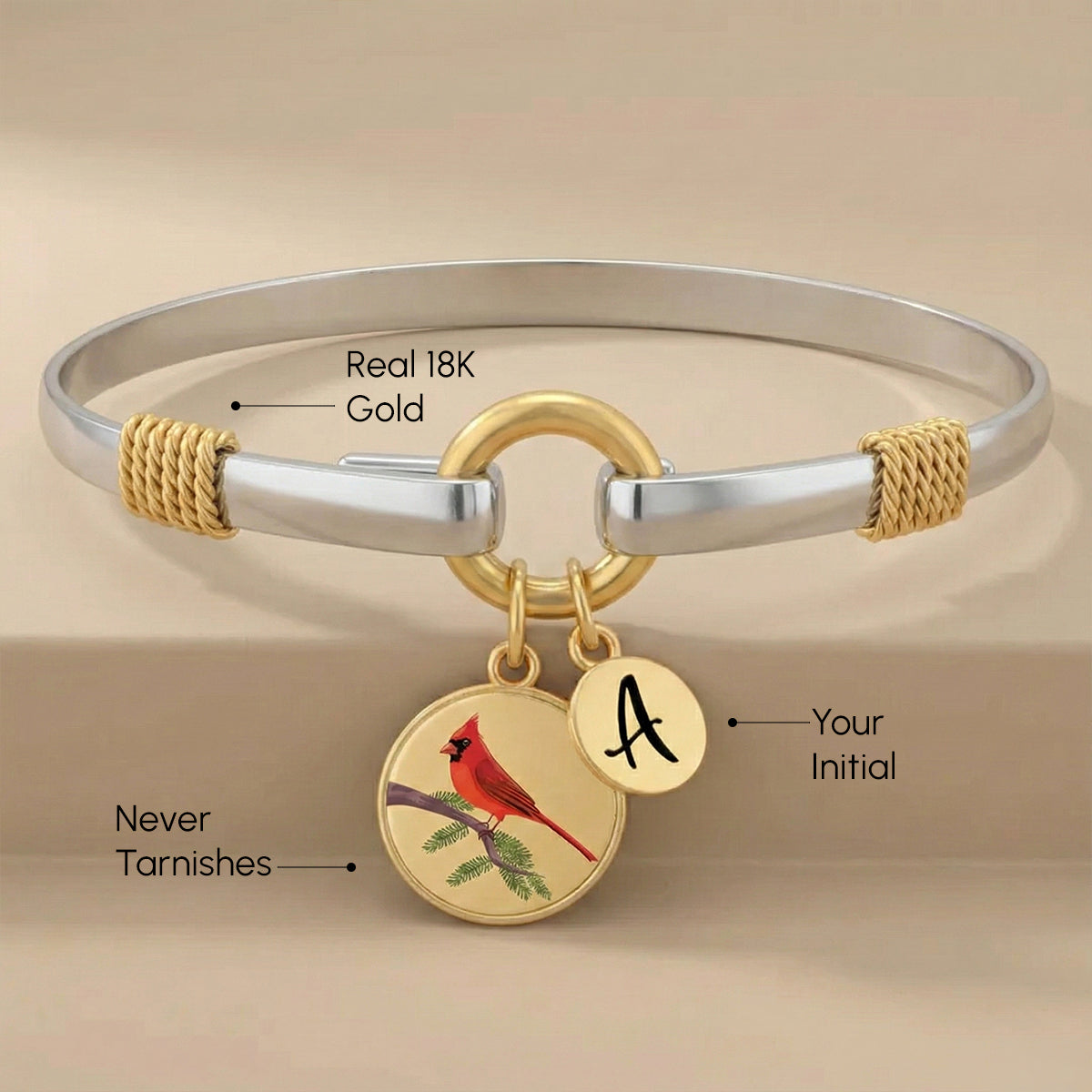 Gold and silver bracelet with cardinal charm and initial pendant on a beige background
