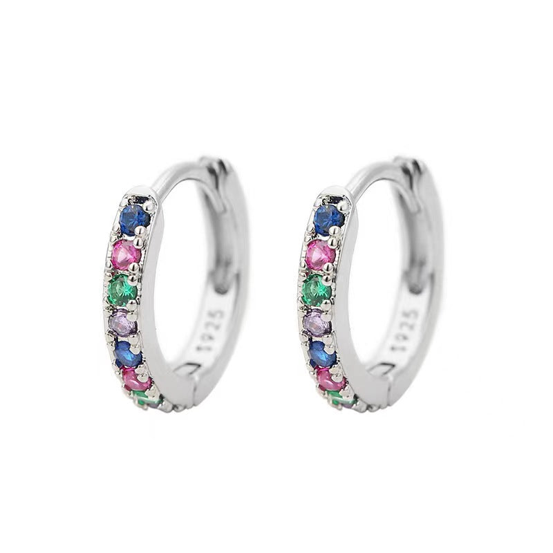 A pair of gold huggie hoop earrings adorned with multicolored gemstones.
