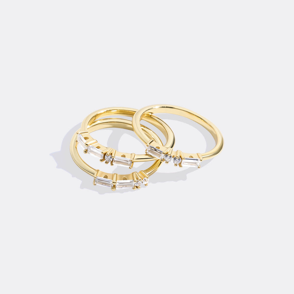 Set of gold rings with diamond accents on a light gray background
