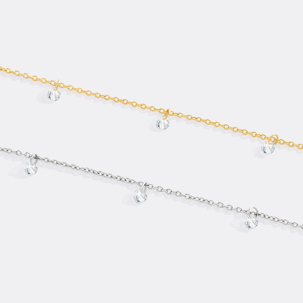 Two gold and silver anklets with clear crystals on a white background