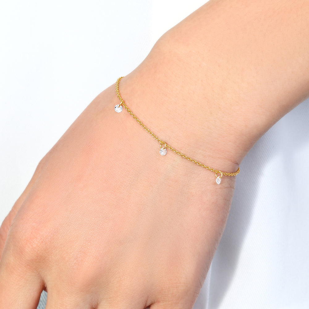 Gold anklet with small heart charms on a person's ankle against a light background