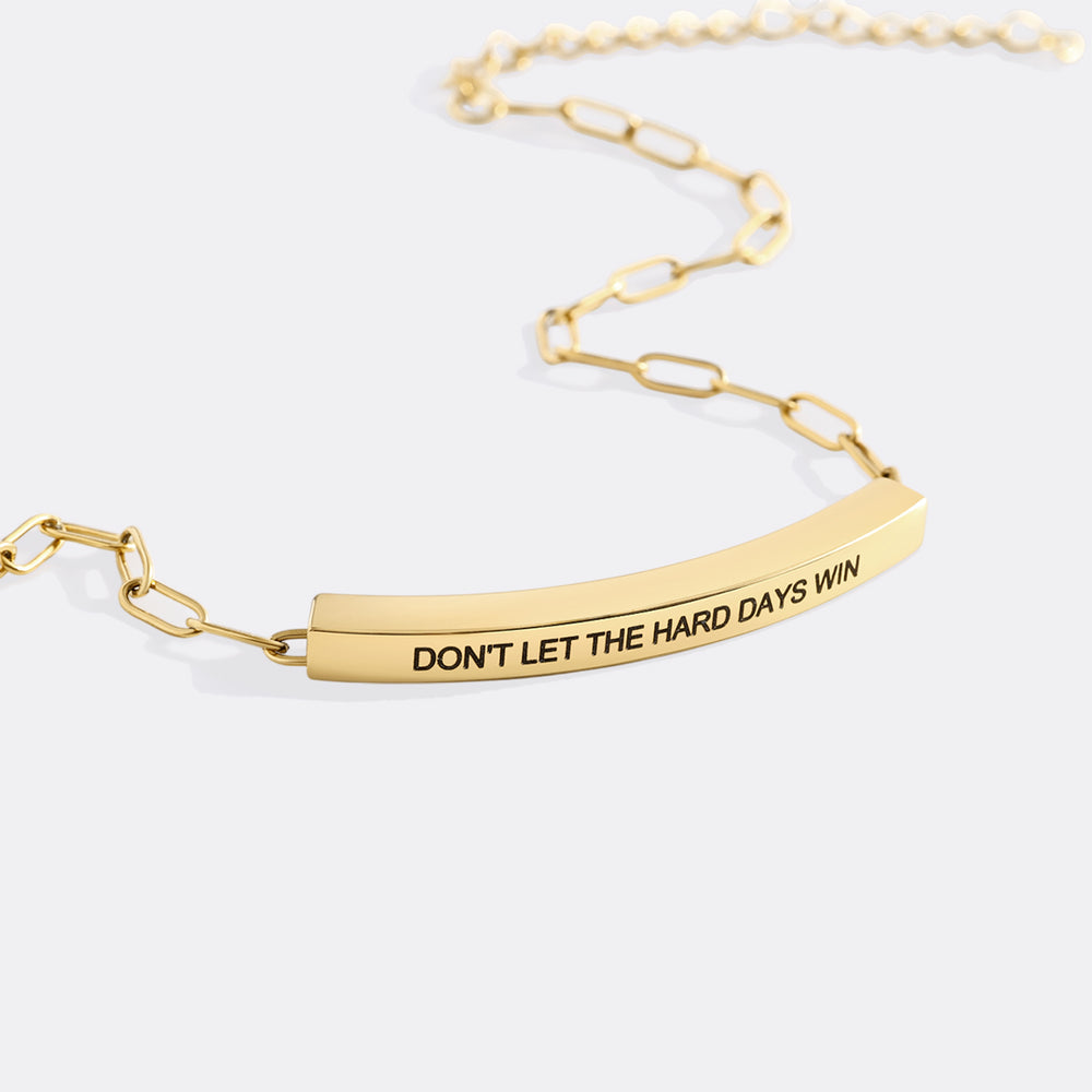 Gold chain bracelet with motivational message on a white background