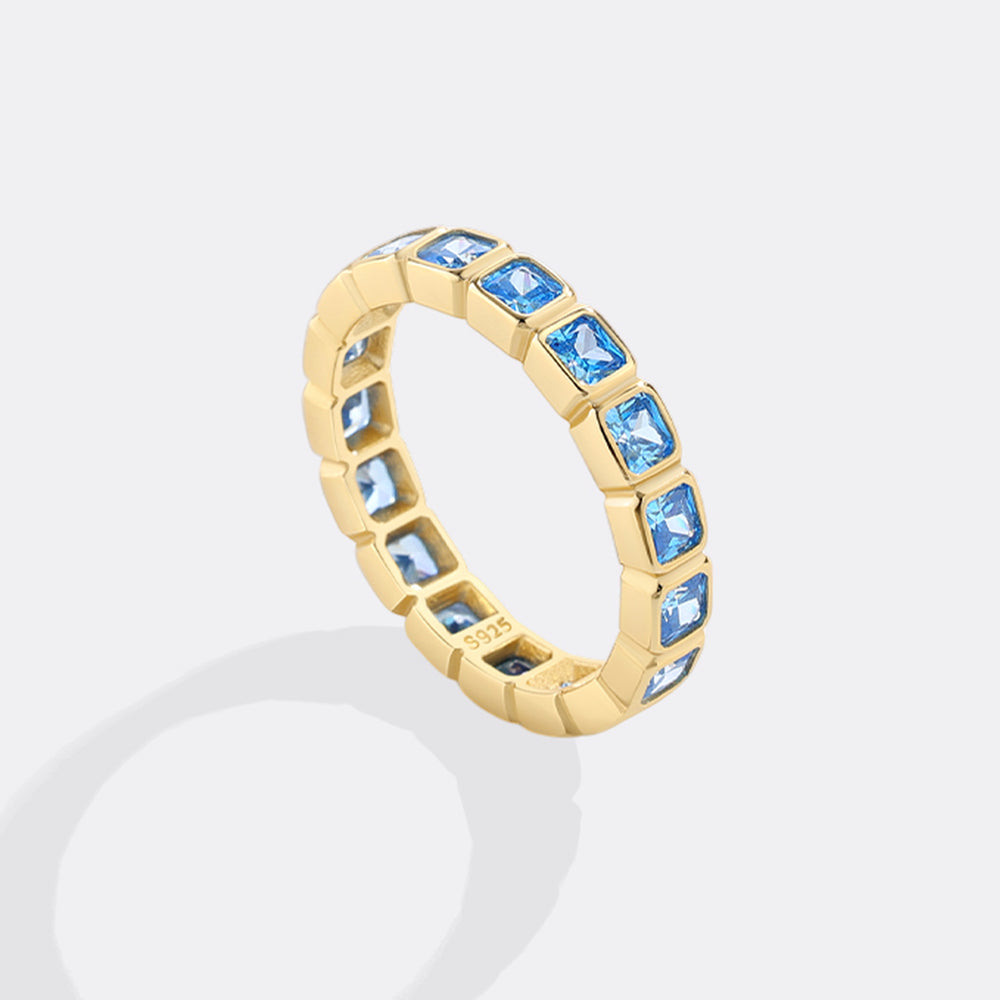 Gold ring with blue gemstones on a white background
