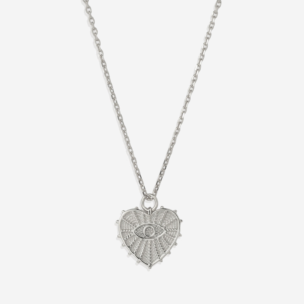 A gold-colored pendant necklace with a heart-shaped charm featuring an evil eye design in the center, displayed against a white background.