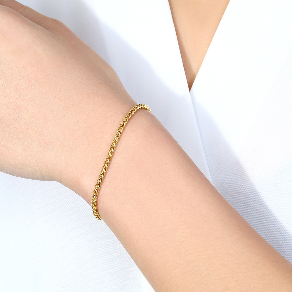 Gold bracelet on a person's wrist with a white background