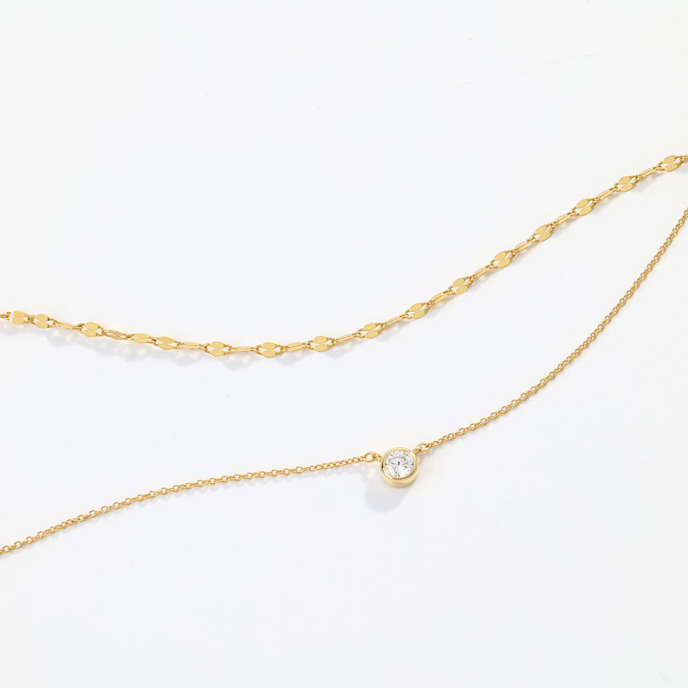 Gold chain necklace with a small pearl pendant on a white background