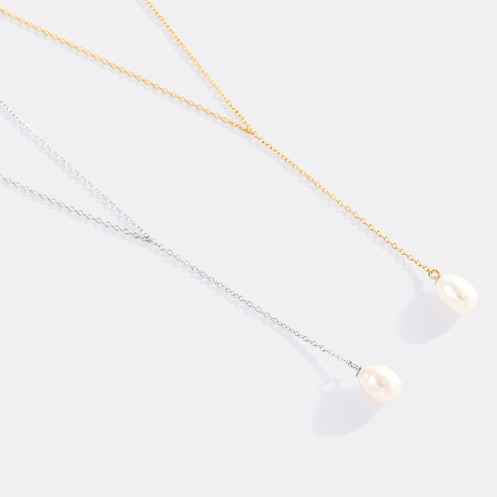 Two pearl necklaces, one gold and one silver, on a light gray background.