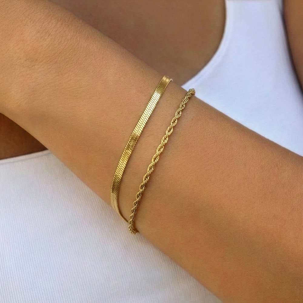 Gold bracelets on a person's wrist against a white background