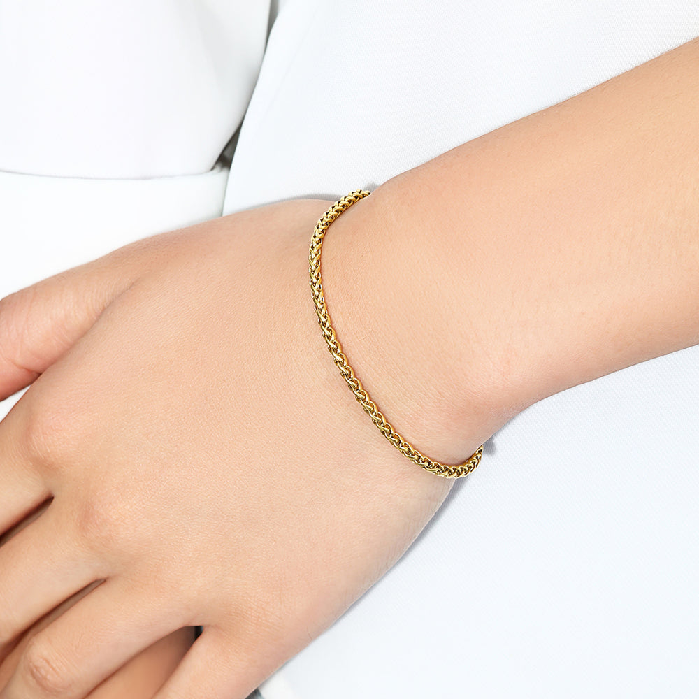 Gold bracelet on a person's wrist with a white background