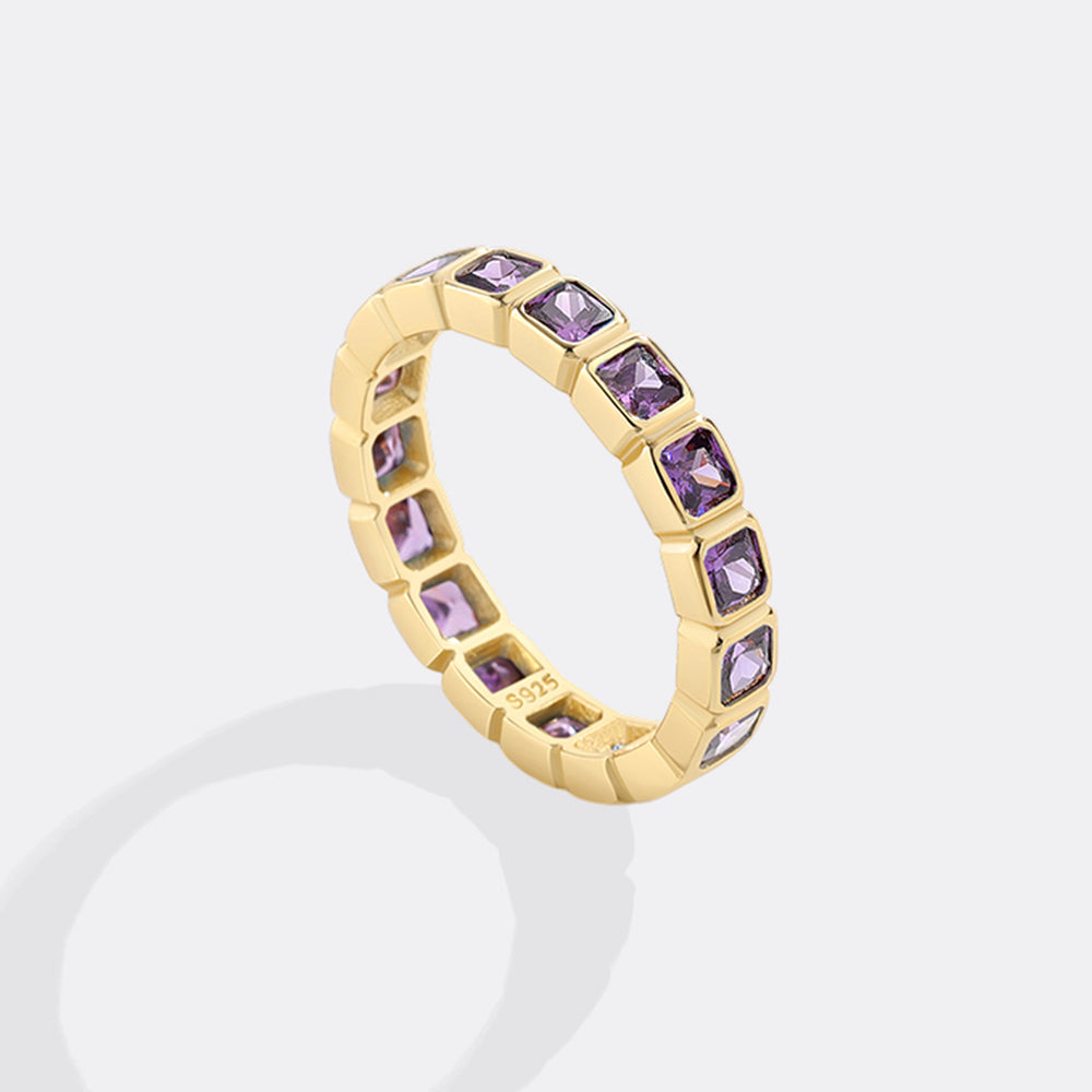 Gold ring with purple gemstones on a white background