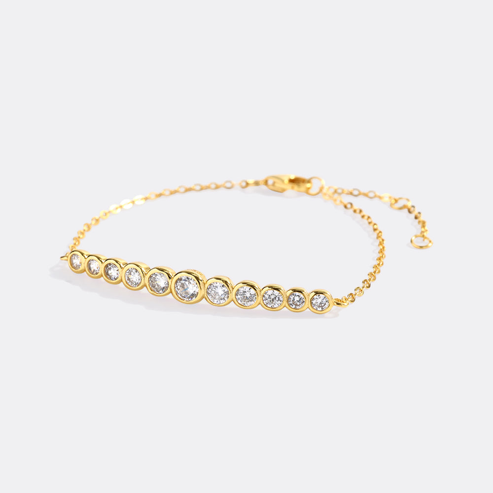 Gold bracelet with clear stones on a light gray background