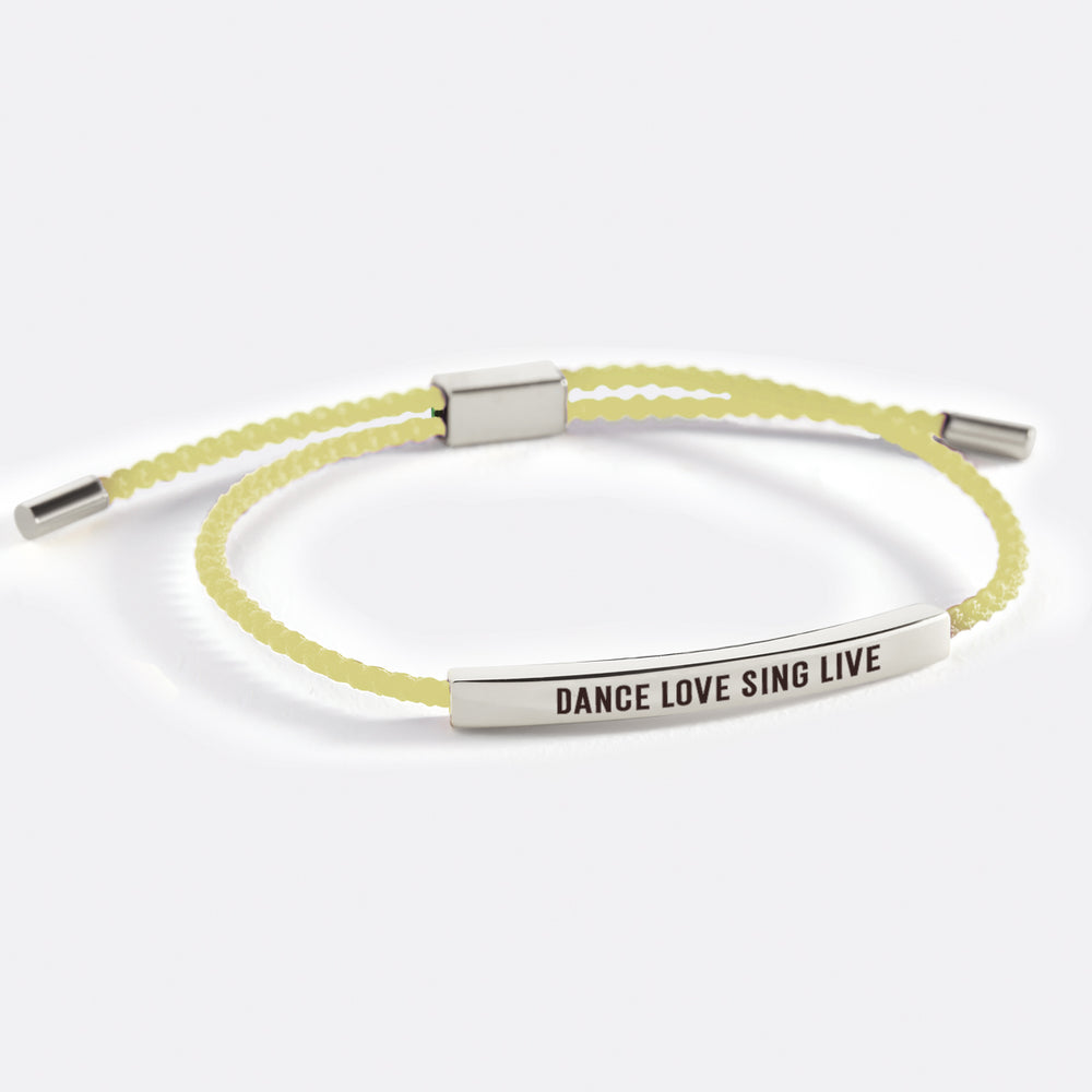 A black inspirational tube bracelet with the words 'DANCE LOVE SING LIVE' printed on it, displayed against a white background with text overlay.