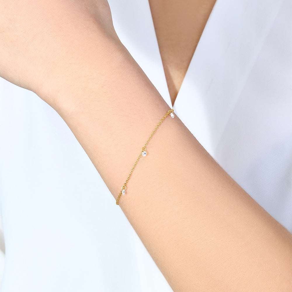 Gold bracelet on a person's wrist against a white background