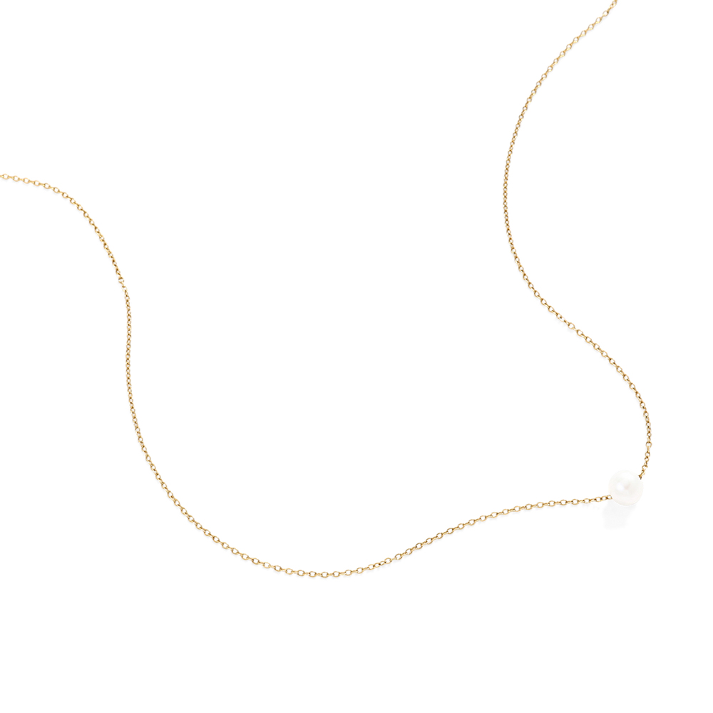 Gold necklace with a small white pendant on a light gray background