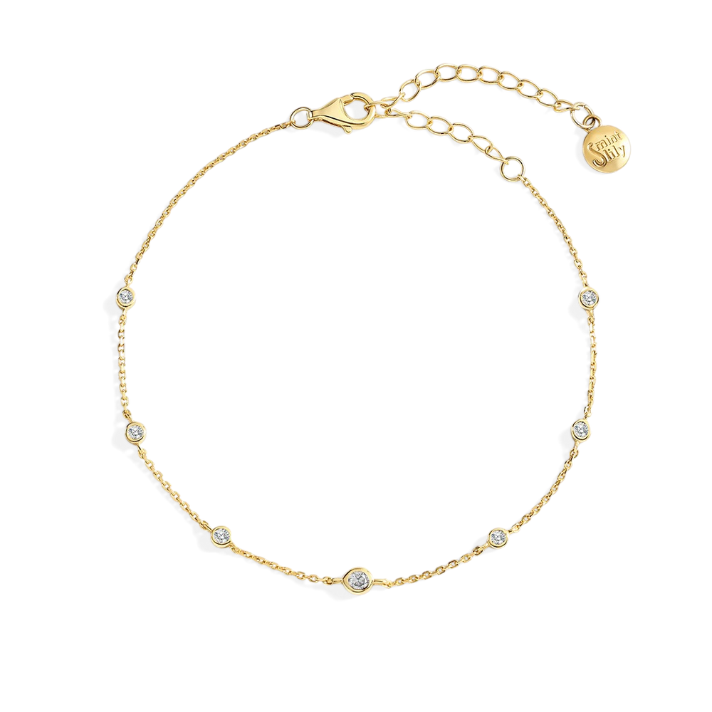 Gold bracelet with small diamonds on a light gray background
