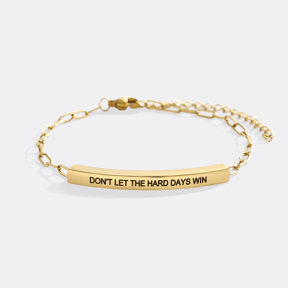 Gold bracelet with motivational message on a white background