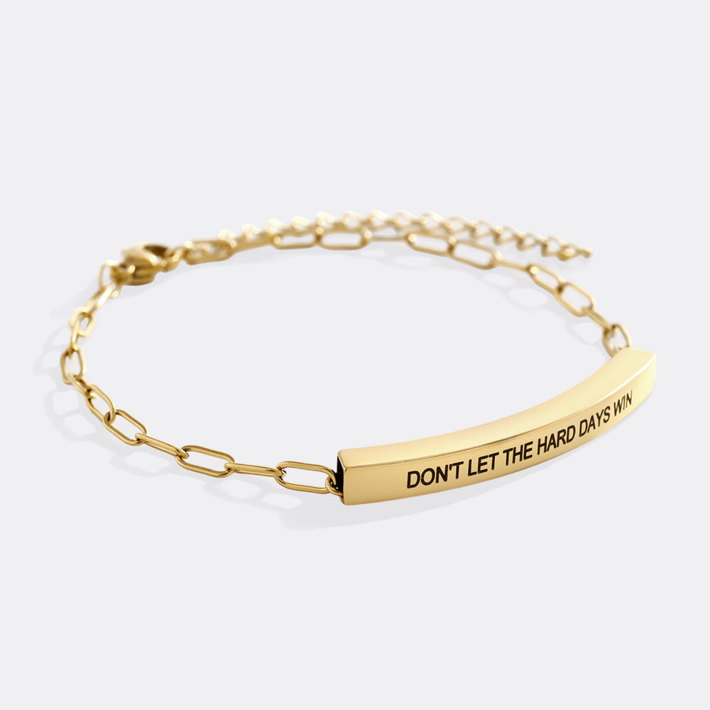 Gold bracelet with motivational message on a white background