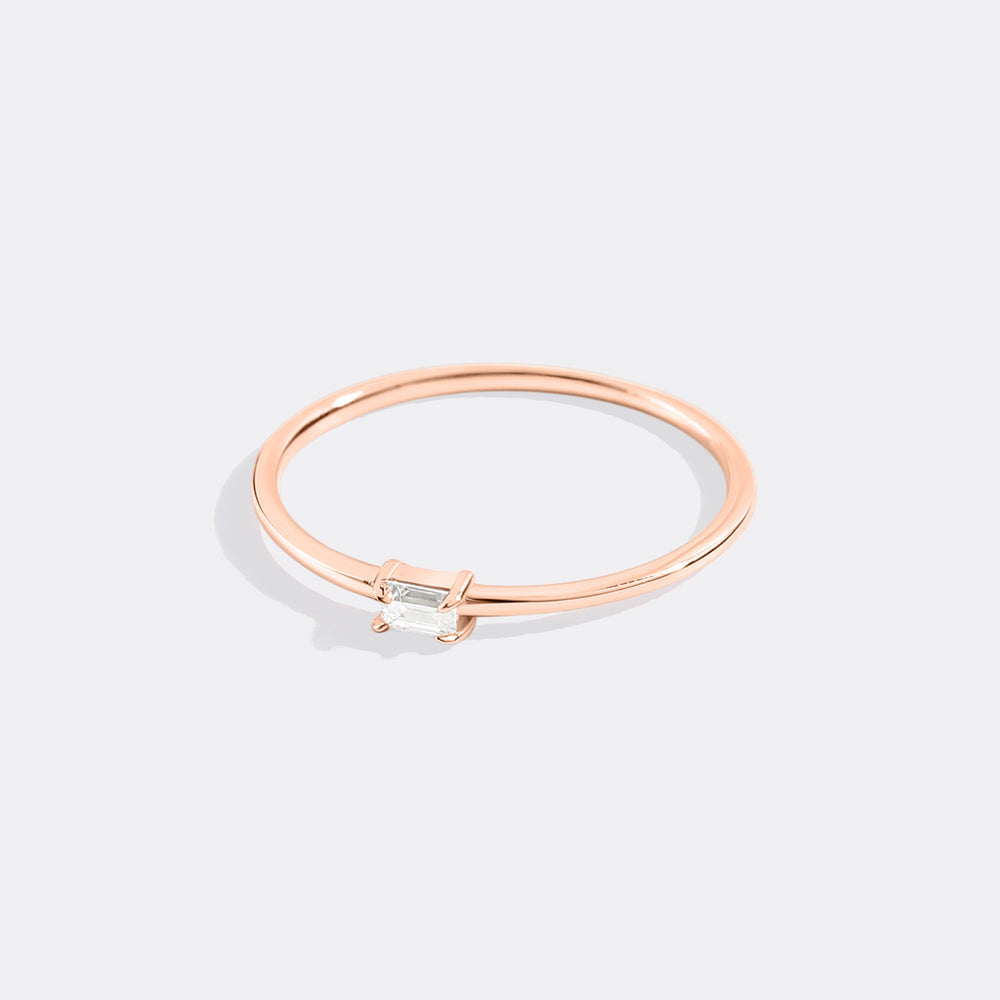 Rose gold ring with a small diamond on a light gray background