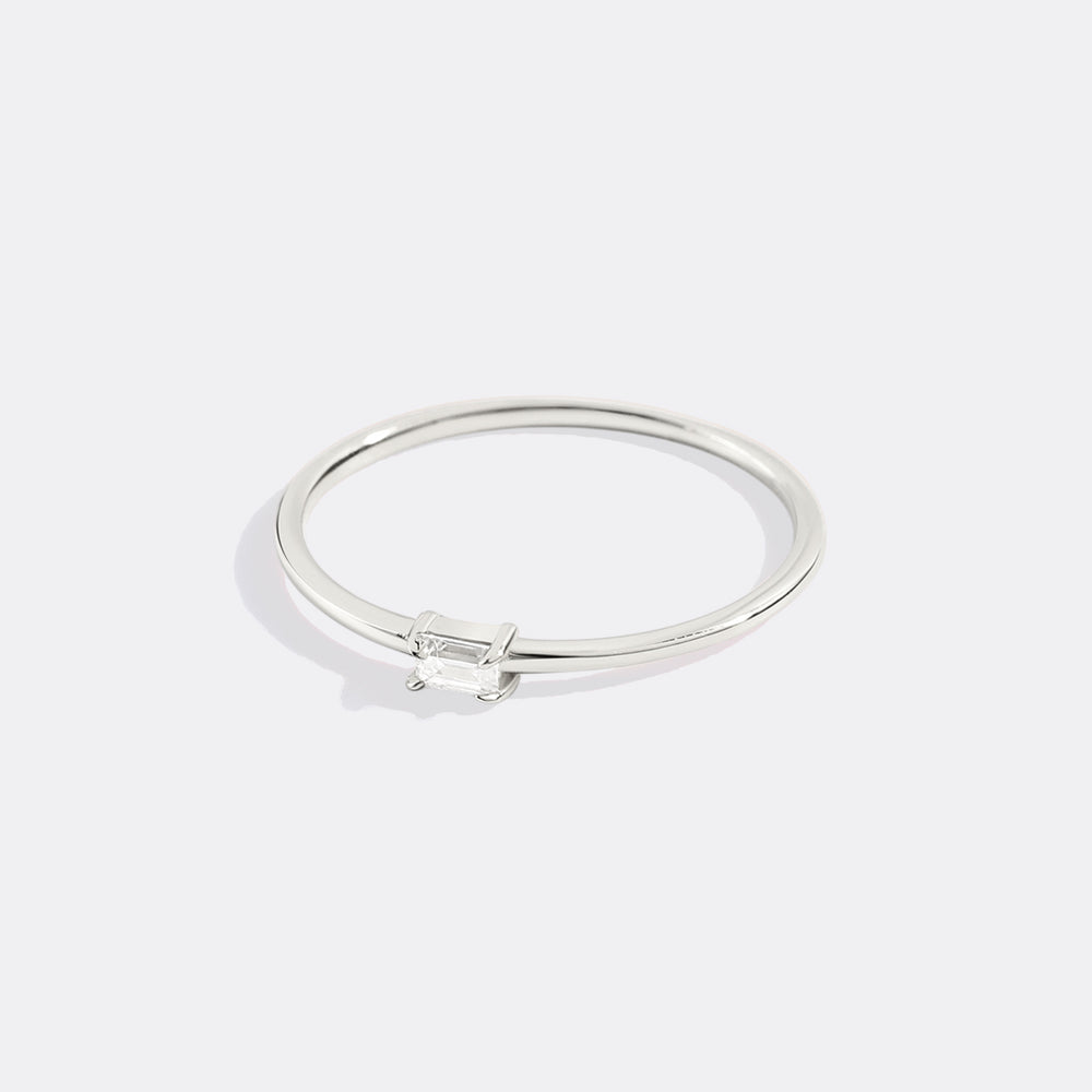 Silver ring with a small diamond on a light gray background