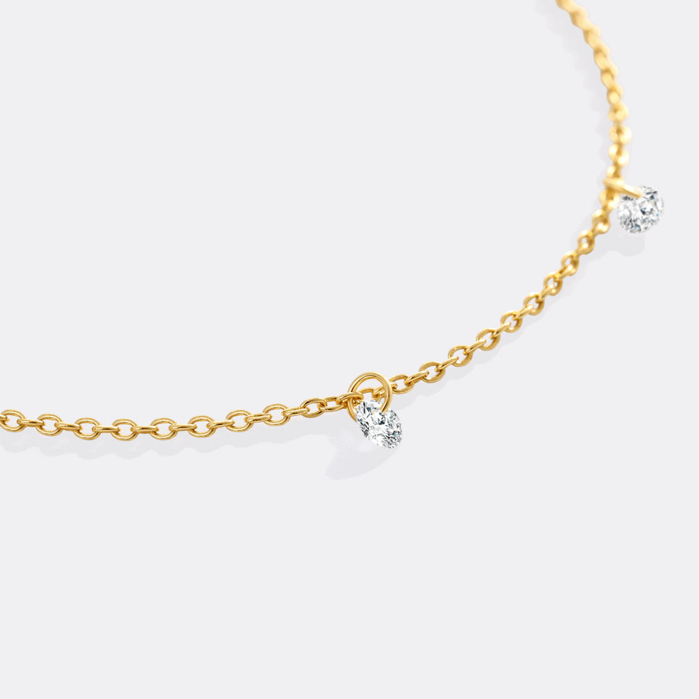 Gold chain necklace with small diamond pendants on a white background