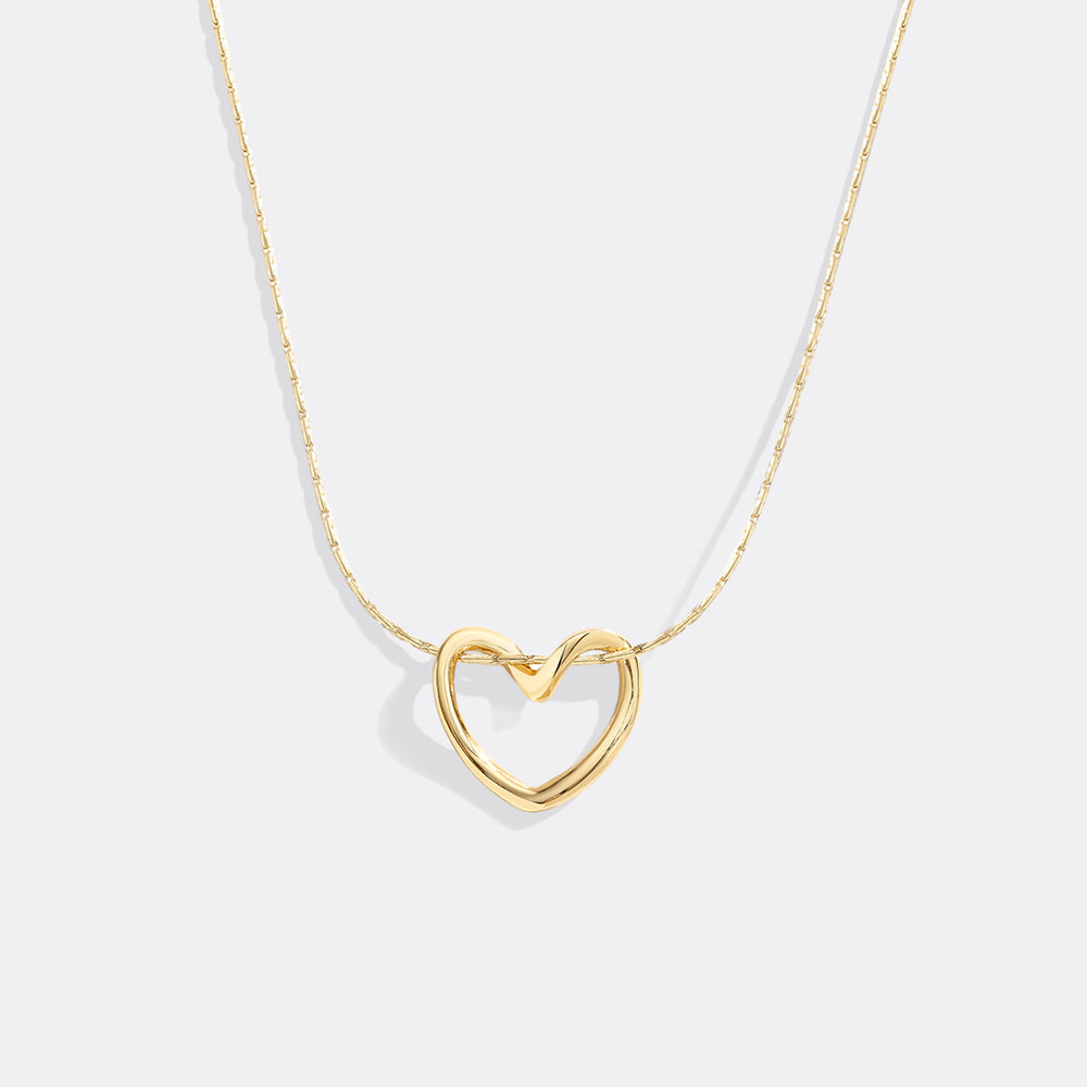Gold heart-shaped necklace on a light gray background