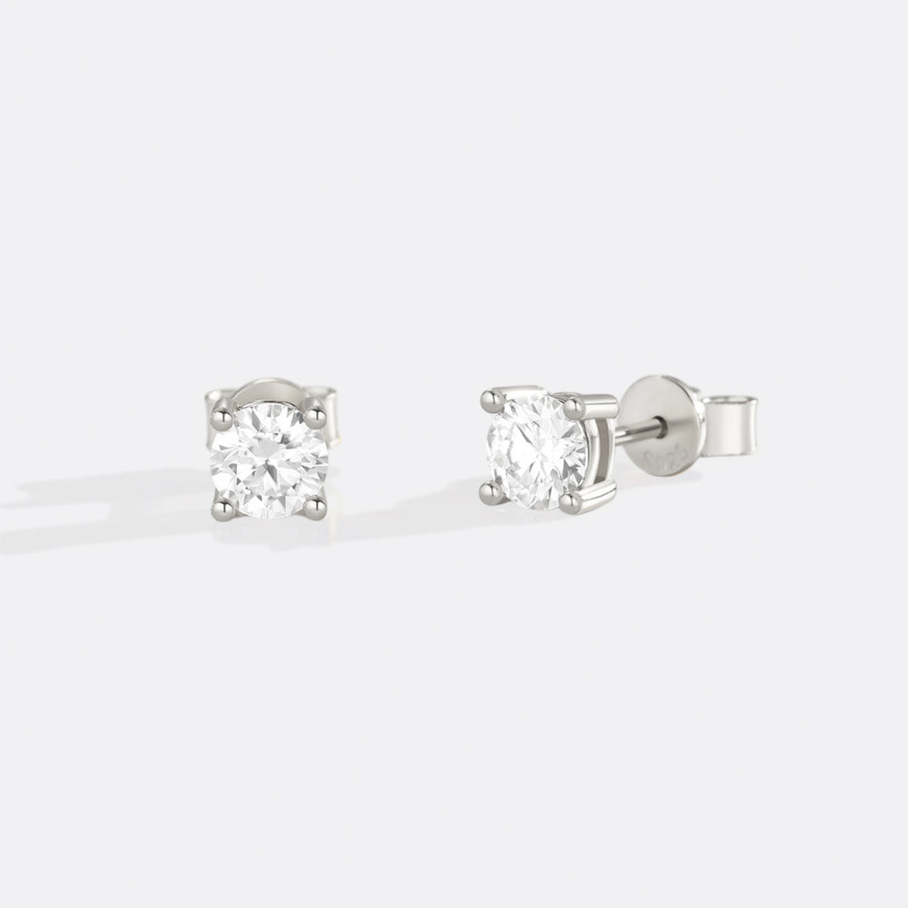 A pair of classic diamond solitaire earrings set in gold.
