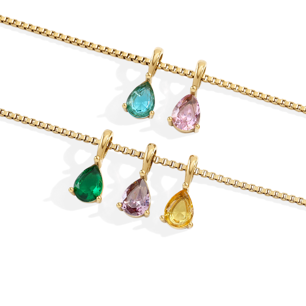 Gold necklaces with teardrop-shaped gemstones on a white background