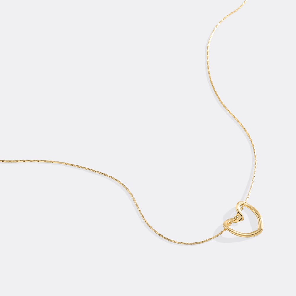 Gold necklace with a heart-shaped pendant on a white background