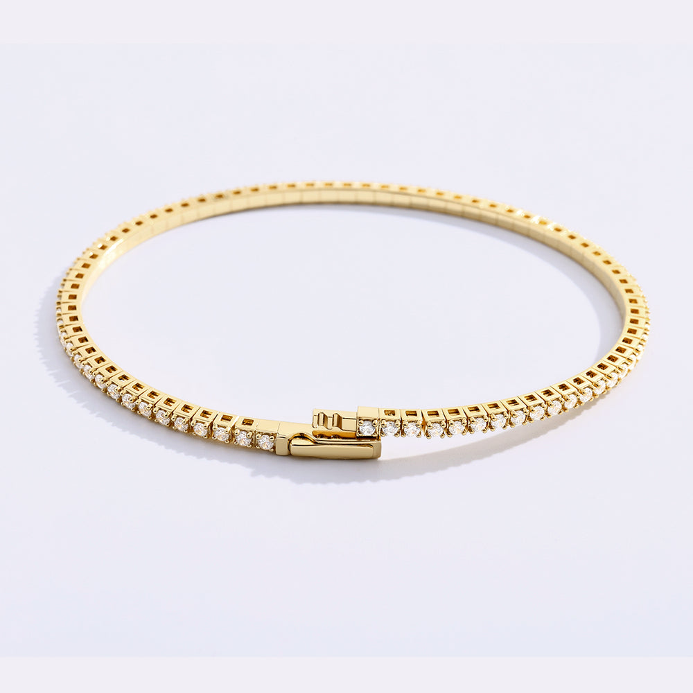 Gold bracelet with diamonds on a light gray background