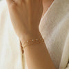 An elegant double chain bracelet accented with fine white accents designed for a refined, understated glow. Video of a model wearing the bracelet, rotating her wrist.