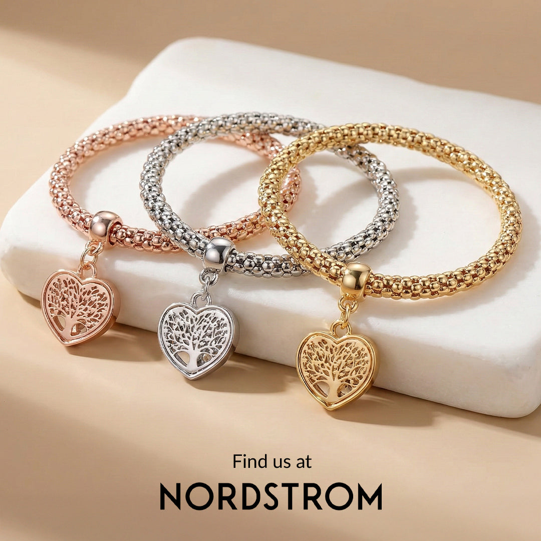 Three heart-shaped charm bracelets in gold, silver, and rose gold on a beige surface with 'Nordstrom' branding.